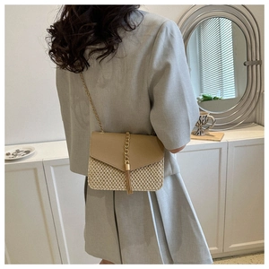 Detail view of khaki leather flap and beige straw woven crossbody bag with gold chain