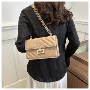 Detail of beige quilted flap bag with chevron pattern and gold chain strap on model