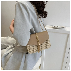 Detail of a woven straw crossbody bag with khaki leather and gold chain fringe