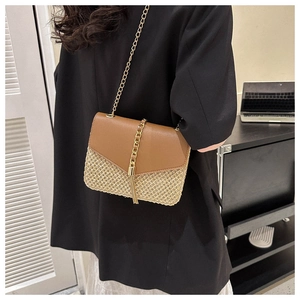 Detail of woven straw and leather contrast handbag with gold chain tassel and strap