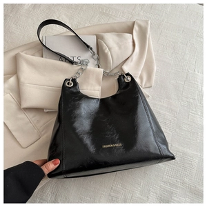 Détail du sac hobo en cuir huilé noir avec logo doré et bandoulière en chaîne argentée