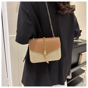 Detail of woven straw crossbody bag with brown leather flap and decorative gold chain