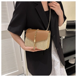 Detail of woven straw crossbody bag with brown leather flap and golden chain strap
