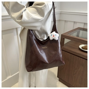 Detail of dark brown faux leather tote bag with star plush charm and fashion label