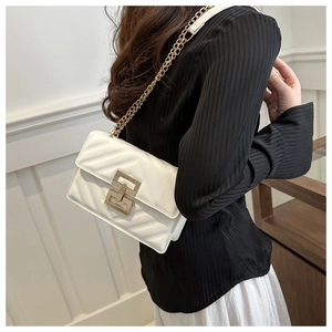 Close-up of white crossbody bag featuring V-quilted texture and gold geometric twist lock