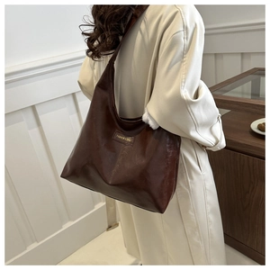 Detail of soft dark brown leather tote bag on model shoulder with rectangular tag