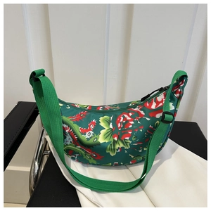 Nahaufnahme der grünen Halbmondtasche mit traditionellen Blumenprints und Gurtband
