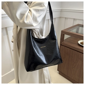 Detail of black glossy faux leather hobo bag with Fashion & Bags metal plaque
