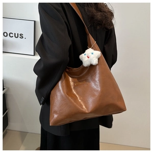 Brown faux leather tote bag with star plush charm and brand logo patch detail