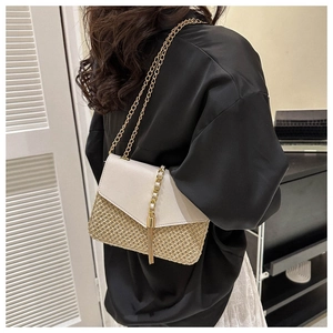 Detail of woven straw crossbody bag with cream leather flap and gold chain strap
