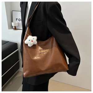 Deep brown large tote bag with star charm shown as a shoulder bag on model