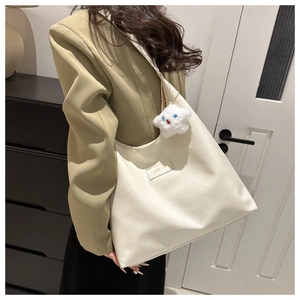 Detail of white large capacity tote bag with star charm and fashion label worn by model