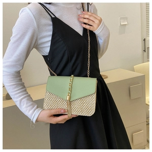 Detail of woven straw crossbody bag with green flap and gold tassel chain strap