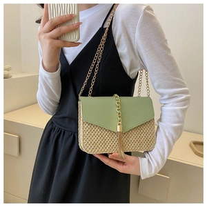 Detailed view of woven straw bag with green leather flap and golden chain fringe