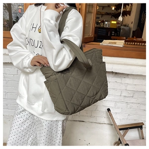 Detail of olive green quilted nylon tote bag featuring side pocket and wide shoulder strap