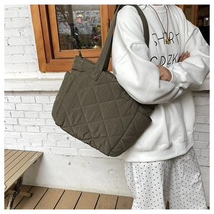 Detailed shot of olive green quilted nylon tote bag with functional side pocket on the body
