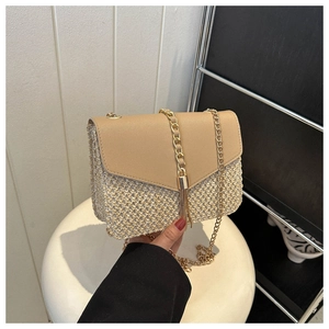 Close-up of woven straw bag with faux leather flap and gold tassel detail