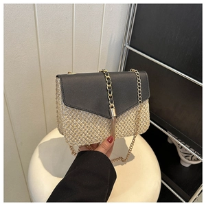 Detail view of woven straw bag with black leather flap and gold tassel buckle