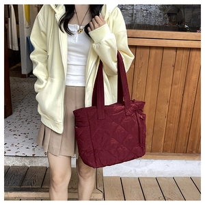 Close-up of wine red quilted nylon tote bag with rhombus pattern and durable shoulder straps