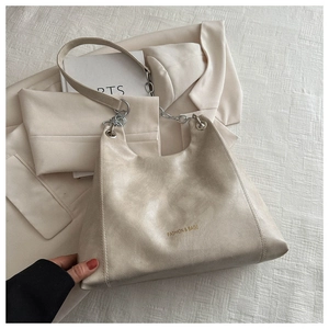 Détail du sac bandoulière en cuir ciré beige avec texte doré et bandoulière chaîne