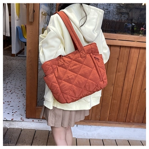 Detailed side view of large caramel nylon tote bag with quilted diamond pattern