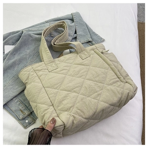 Top view of beige quilted nylon tote bag with rhombus pattern on denim shirt background