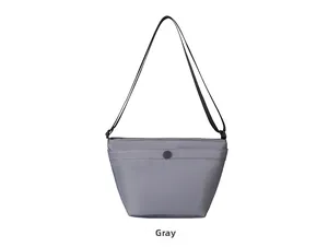 Detalle de bolso tipo cubo de nailon gris con correa negra y bolsillo con botón