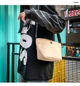 Primer plano de bolso bandolera de nailon beige con botón a presión y correa negra