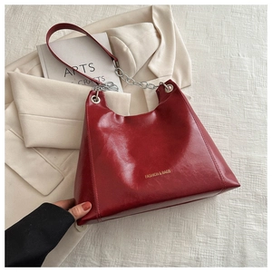 Détail du grand sac cabas en cuir ciré rouge avec chaîne argentée et lettrage doré