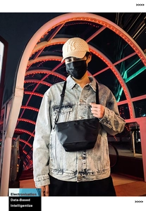 Primer plano de bolso bandolera de nailon negro con cremallera en entorno urbano neón