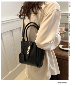 Close-up of black leather bucket bag featuring gold twist-lock and fashion hangtag