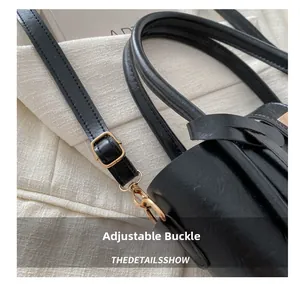 Dettaglio della borsa tote in pelle nera con fibbia regolabile dorata sulla tracolla