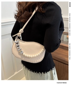 Gros plan du sac hobo beige avec chaîne de perles et de cœurs en argent sur un modèle élégant