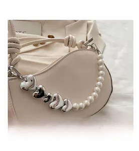 Détail du sac crème avec chaîne en perles et cœurs argentés sur cuir mat élégant