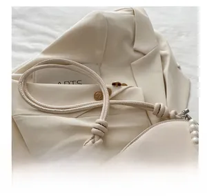 Gros plan du sac en PU crème avec bandoulière en perles et boucle en forme de cœur argenté