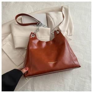 Gros plan détaillé d'un sac bandoulière en cuir ciré marron avec chaîne dorée chic