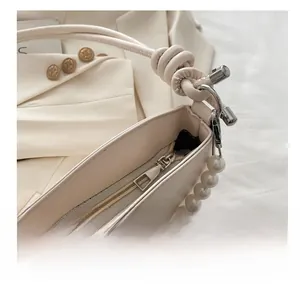 Détail du sac à main blanc crème avec fermeture éclair dorée et chaîne en perles