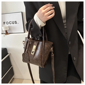 Dettaglio borsa vintage in pelle marrone con chiusura metallica e targhetta