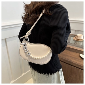 Détail du sac selle crème avec breloque cœur argentée et bandoulière en perles
