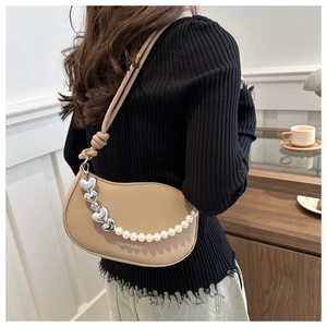 Détail d'un sac selle beige avec breloques cœur en perles et lettrage fashion imprimé