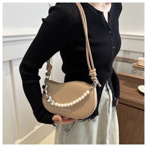 Détail du sac selle beige avec chaîne en perles et ornement de pendentif coeur