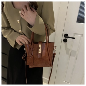 Detail of vintage brown shoulder bag with golden twist lock and adjustable strap