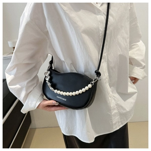 Détail du sac selle noir en demi-lune avec chaîne en perles et logo mode imprimé