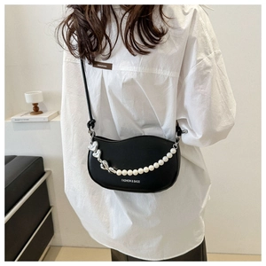 Détail du sac selle noir avec chaîne en perles et cœurs argentés sur chemise blanche