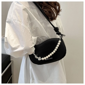 Détail d'un sac à main en cuir noir mat avec chaîne en perles et imprimé blanc