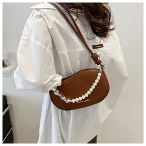 Sac selle marron demi-lune avec chaîne de perles et de cœurs sur chemise blanche