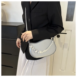Détail du sac demi-lune argenté avec chaîne perle cœur et finition métallisée