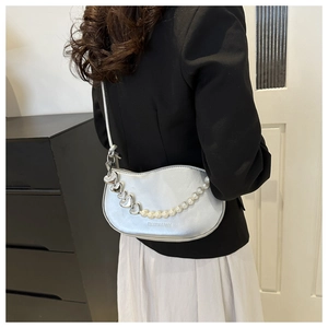 Gros plan d'un sac hobo argenté avec chaîne cœur et perles sur un mannequin