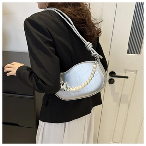 Sac demi-lune argenté avec chaîne de perles porté par un mannequin dans un cadre pro