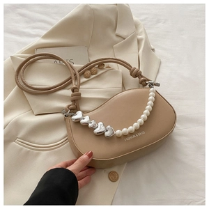 Détail du sac selle beige avec chaîne décorative en perles et cœurs argentés